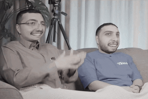 two men are sitting on a couch and one has a shirt that says ytball