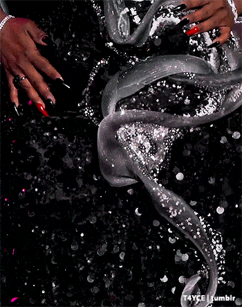 a close up of a woman 's hand holding a silver object in a blurry photo .
