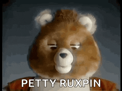 a teddy bear with its eyes closed and the words `` petty ruxpin '' written on it .
