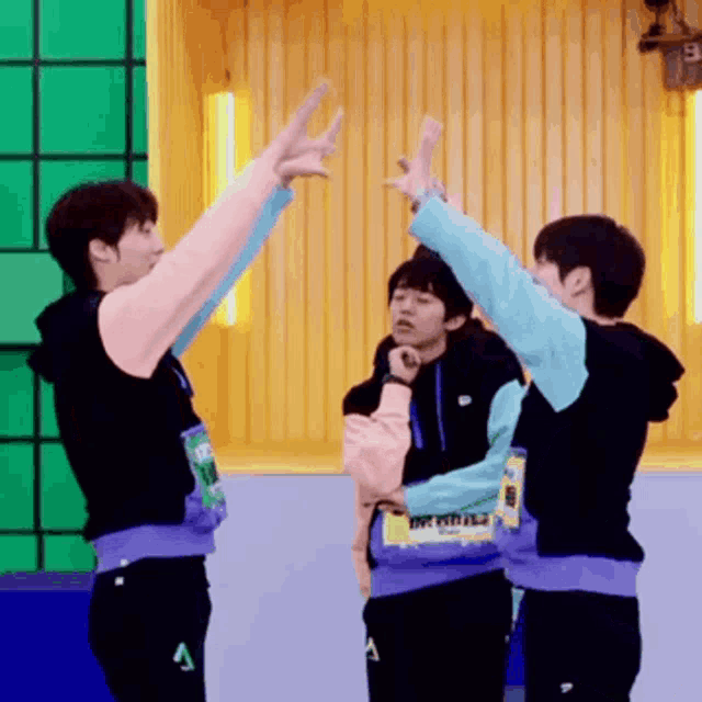 a group of young men are giving each other a high five in front of a yellow wall