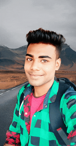 a young man in a green plaid shirt is smiling for the camera
