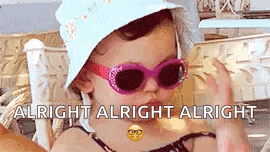 a little girl wearing sunglasses and a hat is sitting on a chair .