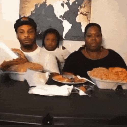 a man , woman and child are sitting at a table eating food .