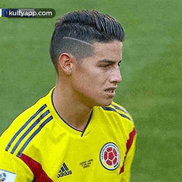 a close up of a soccer player wearing a yellow adidas jersey