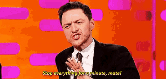 a man in a suit and tie is making a face and saying `` stop everything for a minute , mate ! ''