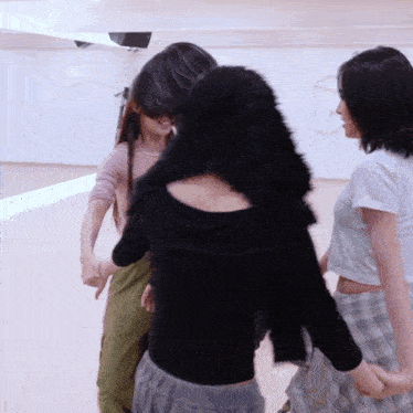 a woman in a black top is holding hands with two other women in a dance studio