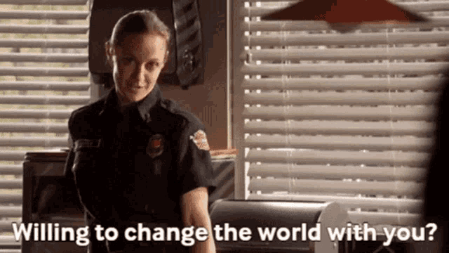 a woman in a police uniform is standing in front of a window and says " willing to change the world with you ? "