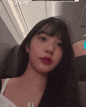 a woman is sitting on an airplane with a screen behind her that says " zz "