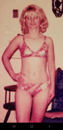 a woman in a bikini stands in front of a chair