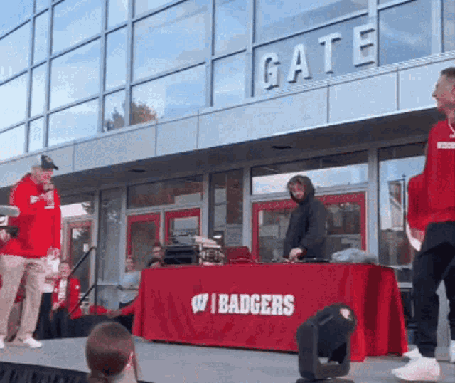 a man stands on a stage in front of a table that says badgers