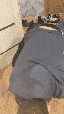 a person laying on their back in front of a dresser with shoes on the floor