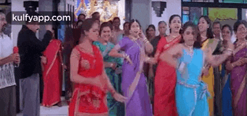 a group of women are dancing in front of a crowd of people .