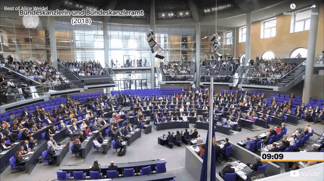 a large auditorium filled with people watching a video titled best of alice wedel bundeskanzlerin und bundeskanzleramt