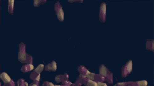 a bunch of pink and yellow pills falling on a black surface .