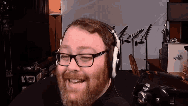 a man with glasses and a beard wears headphones