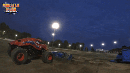 a monster truck is jumping over a pile of cars at a monster truck throwdown race