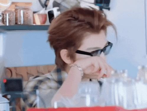 a man wearing sunglasses and a plaid shirt is standing in front of a counter .