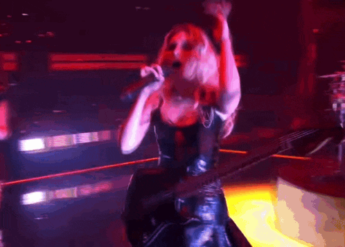 a woman is singing into a microphone while playing a guitar