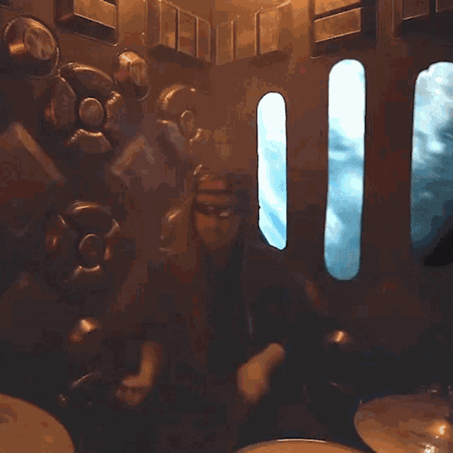 a man playing drums in a dark room with a window
