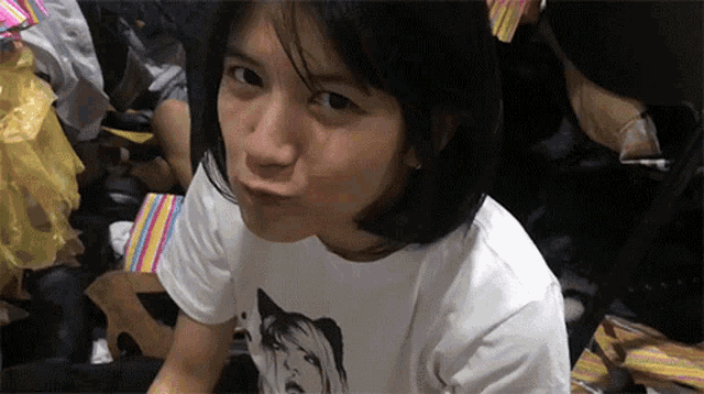 a woman wearing a white shirt with a cat on it makes a funny face
