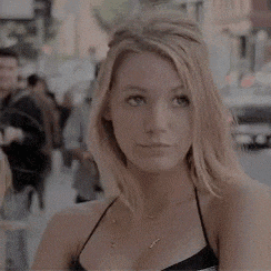 a woman in a black top is standing on a city street .