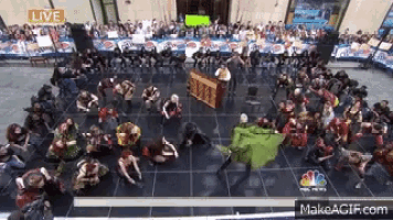 a large group of people are dancing on a stage with a nbc news logo in the background