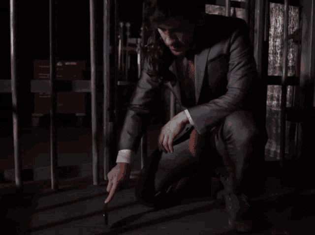 a man in a suit and red tie is kneeling down and pointing at something