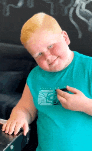 a young boy with blonde hair is wearing a blue shirt that says ' xtreme ' on it