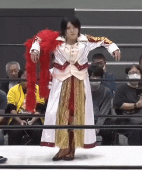 a woman in a white and gold dress is standing in a ring holding a red boa