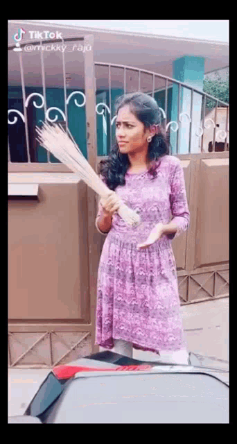 a woman in a purple dress is holding a broom in her hand