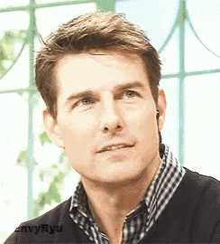 a close up of a man wearing a black sweater and a plaid shirt