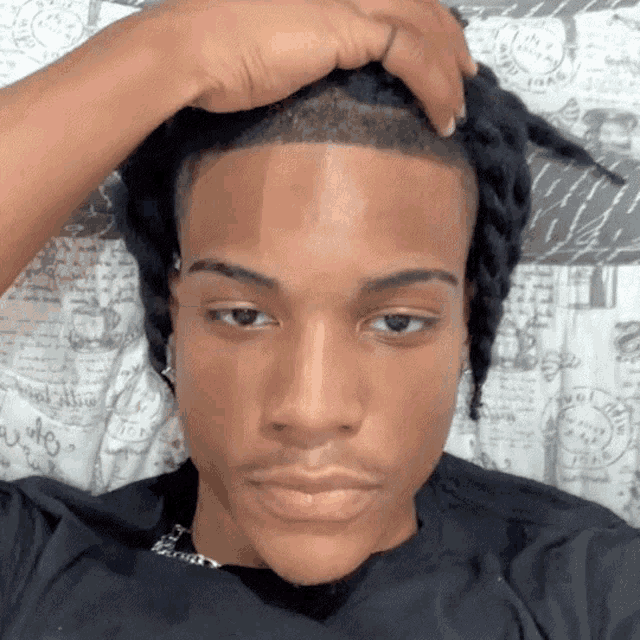 a young man with dreadlocks is laying on a bed and touching his head