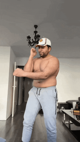 a shirtless man in a white hat is dancing in a room
