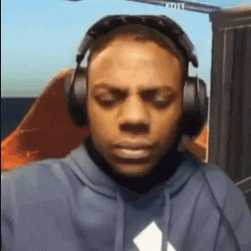 a man wearing headphones and a hoodie looks at the camera