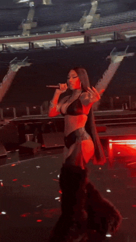 a woman in a red top and black leather pants is dancing with her arms in the air .
