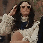 a woman in a white sweater and sunglasses is sitting next to a man .