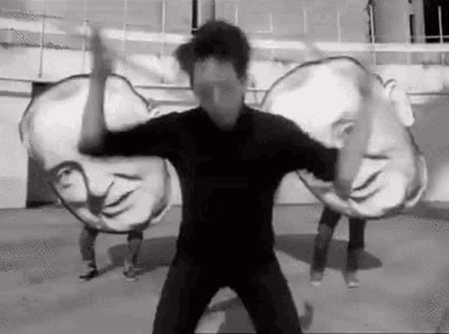 a man is dancing in front of a group of people holding huge heads .
