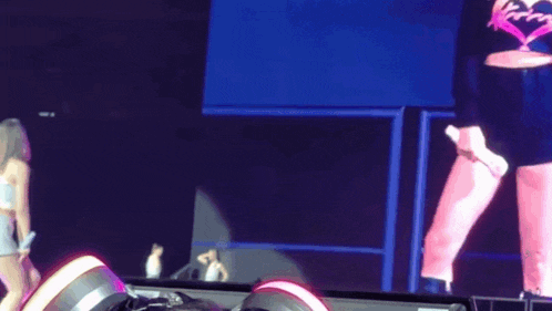 a woman is standing on a stage in front of a large screen with a heart on it .