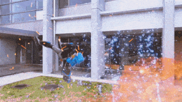 a person is doing a trick in front of a building with fire coming out of it