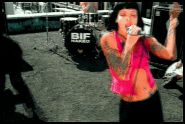 a woman singing into a microphone in front of a bif naked drum
