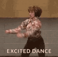 a man is dancing in front of a brick wall with the words `` excited dance '' written below him .