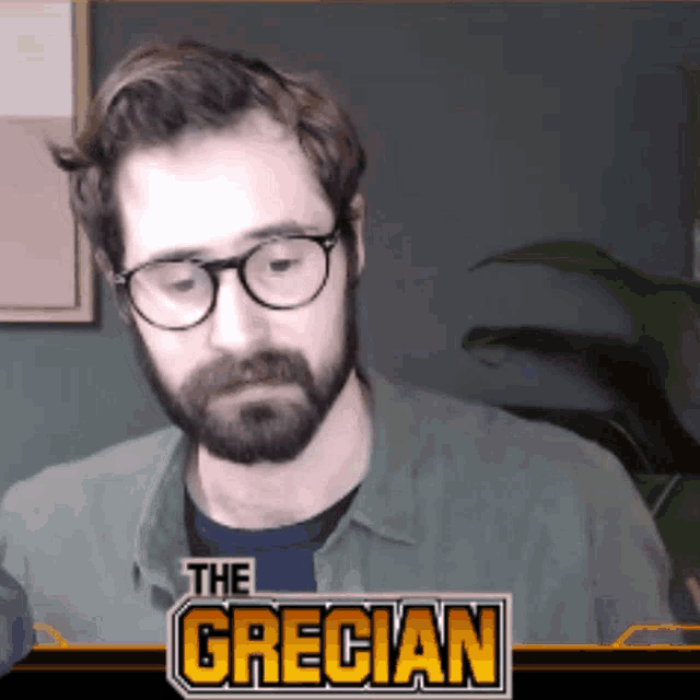 a man with glasses and a beard is on a screen with the name the grecian