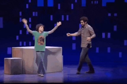 a man and a boy are dancing on a stage and the boy is wearing a green shirt with a bear on it