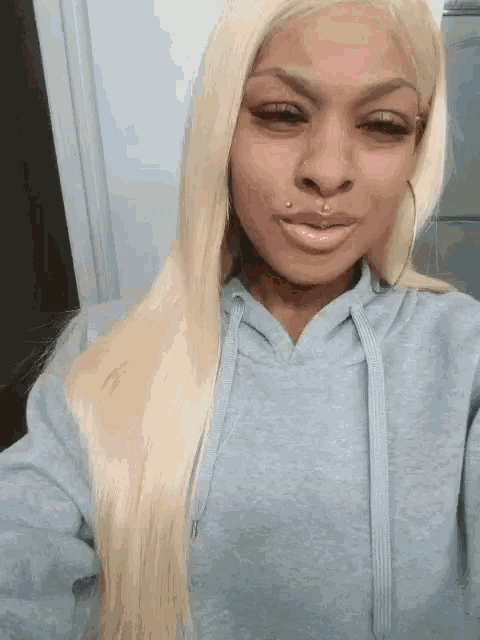 a woman with blonde hair is wearing a gray hoodie