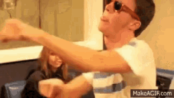 a man wearing sunglasses is dancing in front of a woman .