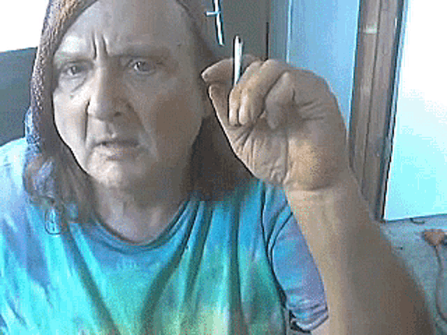 a woman in a tie dye shirt is holding a pen in her right hand