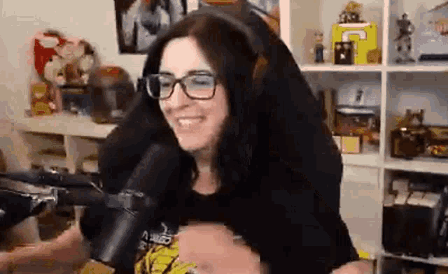 a woman wearing glasses is sitting in front of a microphone .