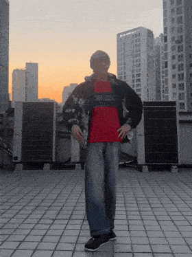 a man wearing a kenzo shirt is standing on a tiled floor