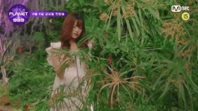 a girl in a white dress is standing in a lush green forest