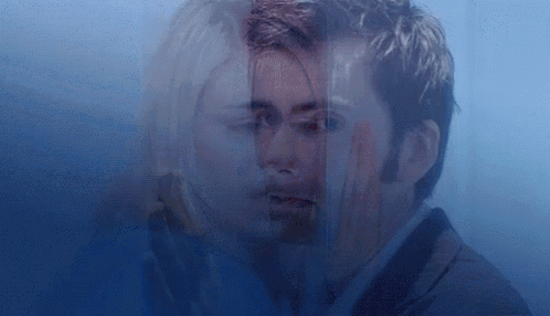 a man and a woman are standing next to each other behind a glass .